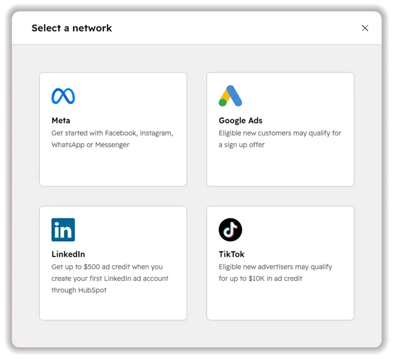 HubSpot's "Select a network" dialog for connecting an ad account, showing four options as cards: Meta (Facebook, Instagram, WhatsApp, Messenger), Google Ads, LinkedIn (up to $500 ad credit), and TikTok (up to $10K ad credit for eligible new advertisers).
