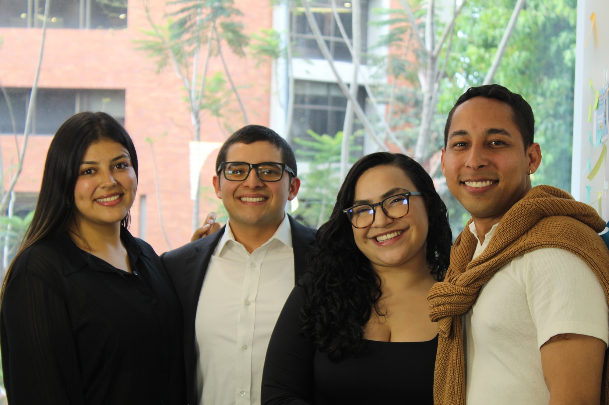 Four members of the On The Fuze team smiling in modern office environment