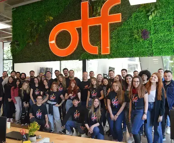 On The Fuze company team photo with employees wearing branded t-shirts in office with living wall